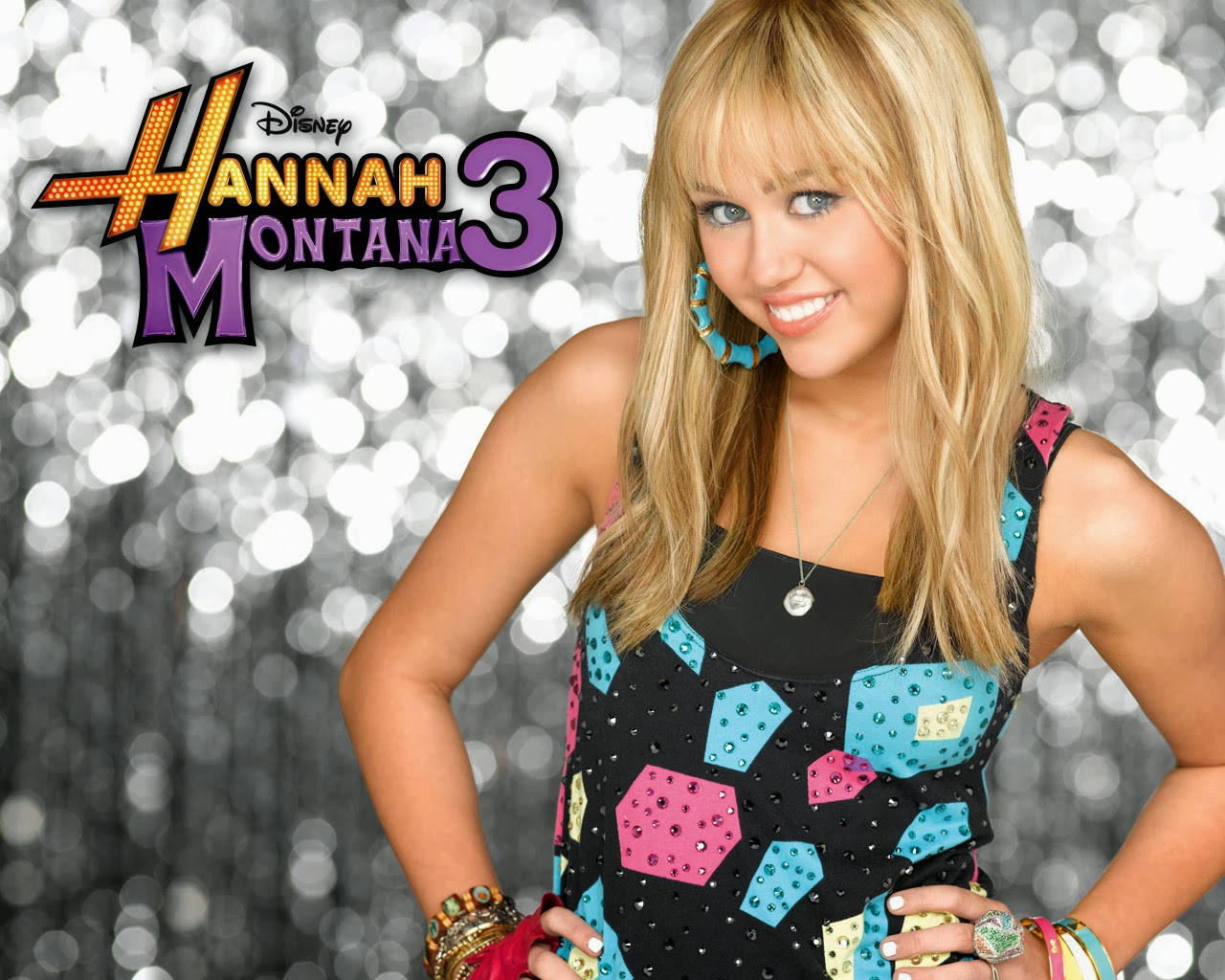 漢娜蒙塔娜準備在第三季登台演出 壁紙 — Hannah Montana 身穿色彩繽紛的亮片上衣，在閃閃發光的銀色背景前自信微笑，背景上還有節目標誌。