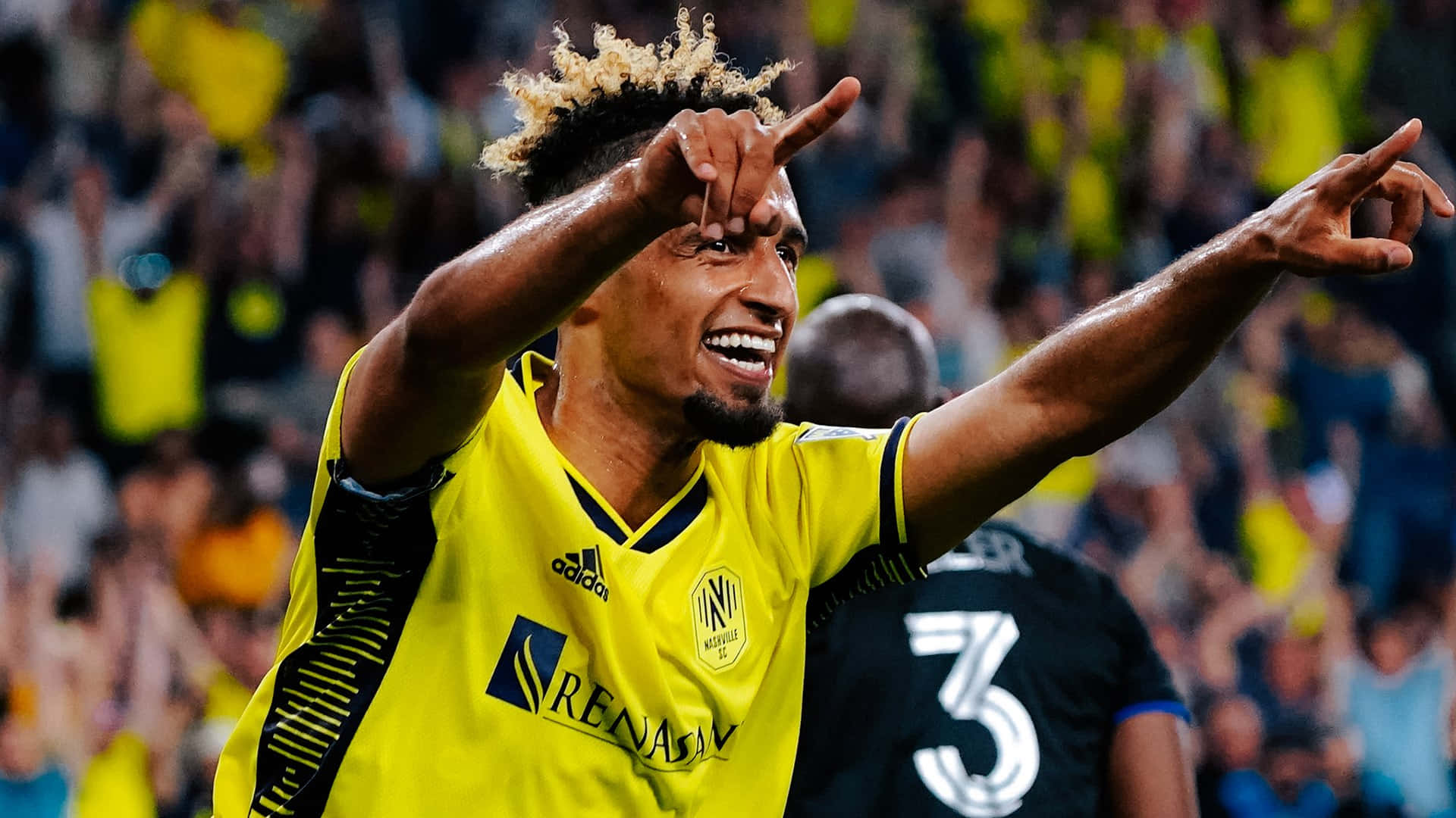 漢尼·穆克塔爾 奧迪 MLS 杯淘汰賽慶祝進球 壁紙 — 一位身穿黃色球衣的快樂足球運動員在體育場燈光下張開雙臂，手指指向人群慶祝。