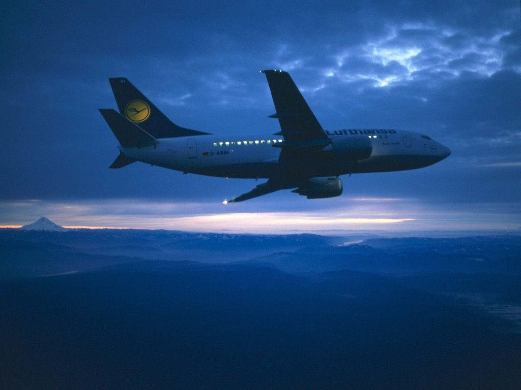 漢莎航空飛機在黃昏時飛越山巒