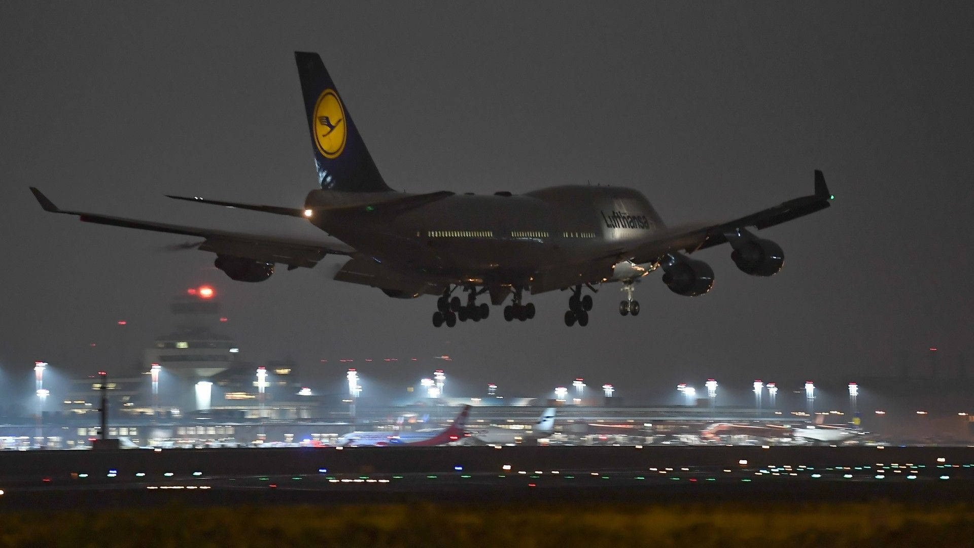 漢莎航空波音747在夜間降落，跑道燈光亮起。