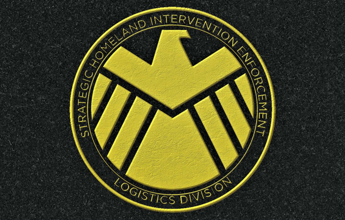 黃色SHIELD Logistics Division標誌徽章，位於黑色紋理背景上。
