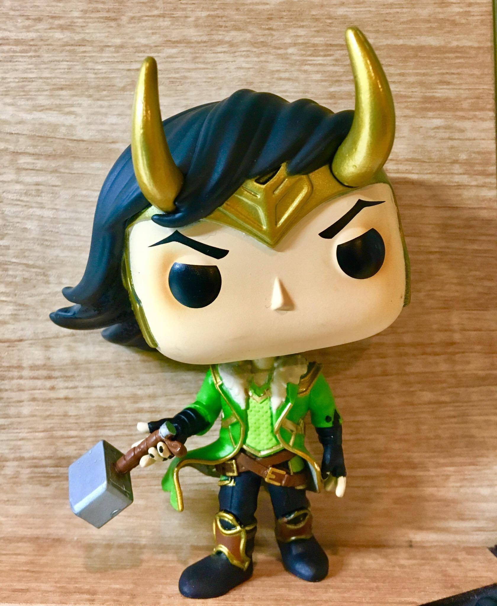 漫威洛基 Funko Pop 壁紙 — 一個Funko Pop! 洛基公仔，金色角，綠色盔甲，手持錘子，放在木質表面上。