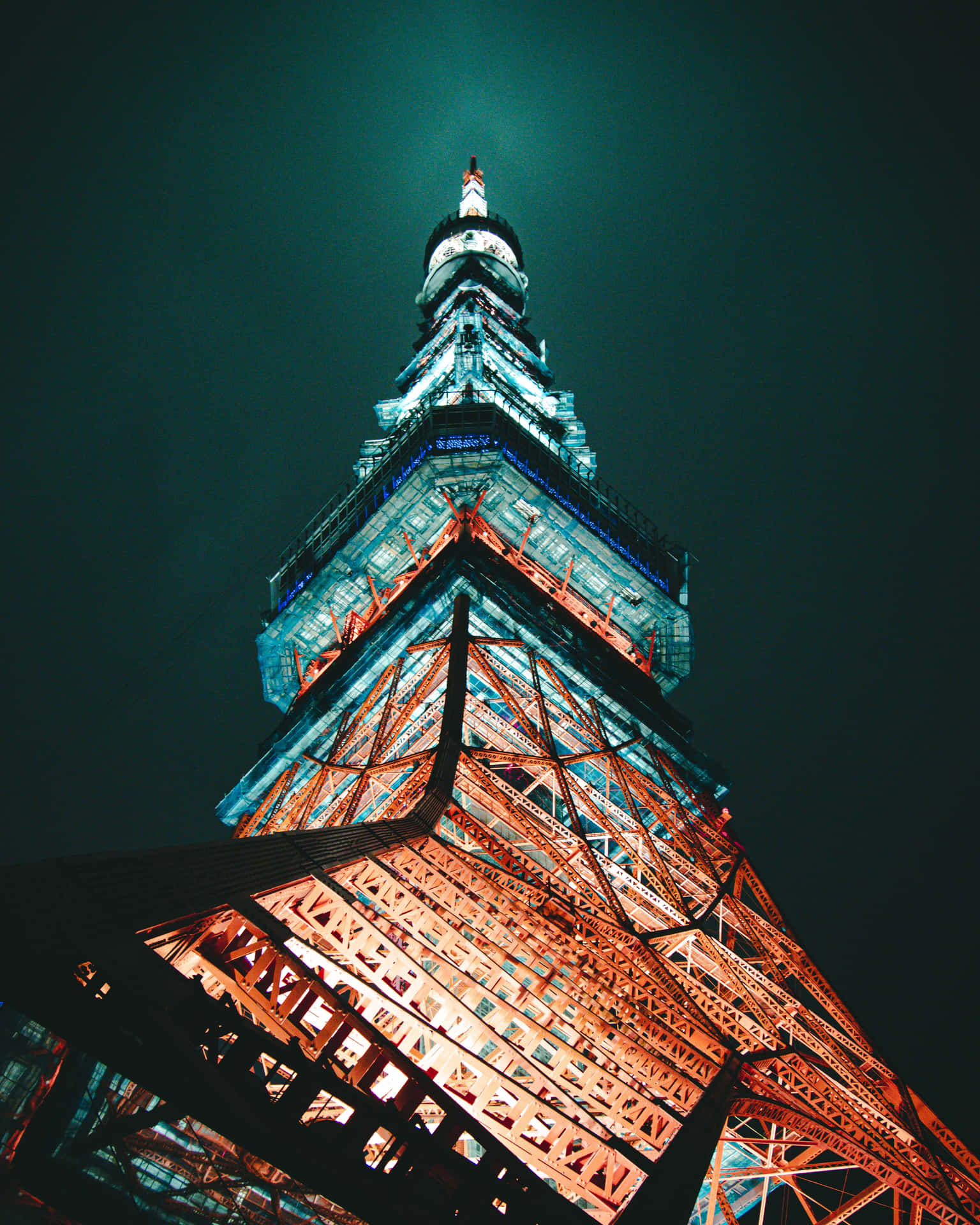 東京鐵塔在夜間被橙色和藍色燈光照亮，背景是黑暗的天空。