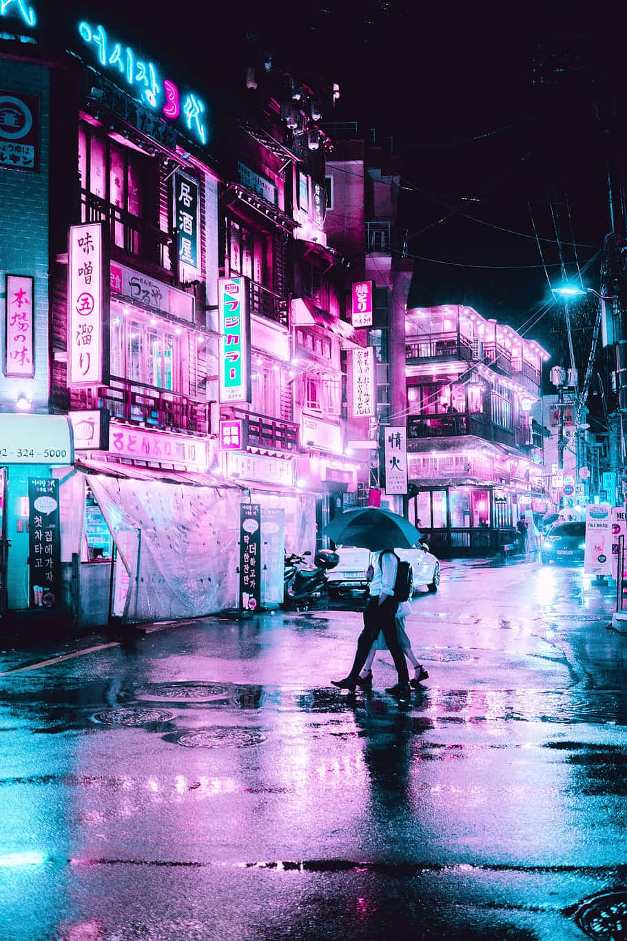 夜晚在潮濕的霓虹城市街道上撐傘行走的人