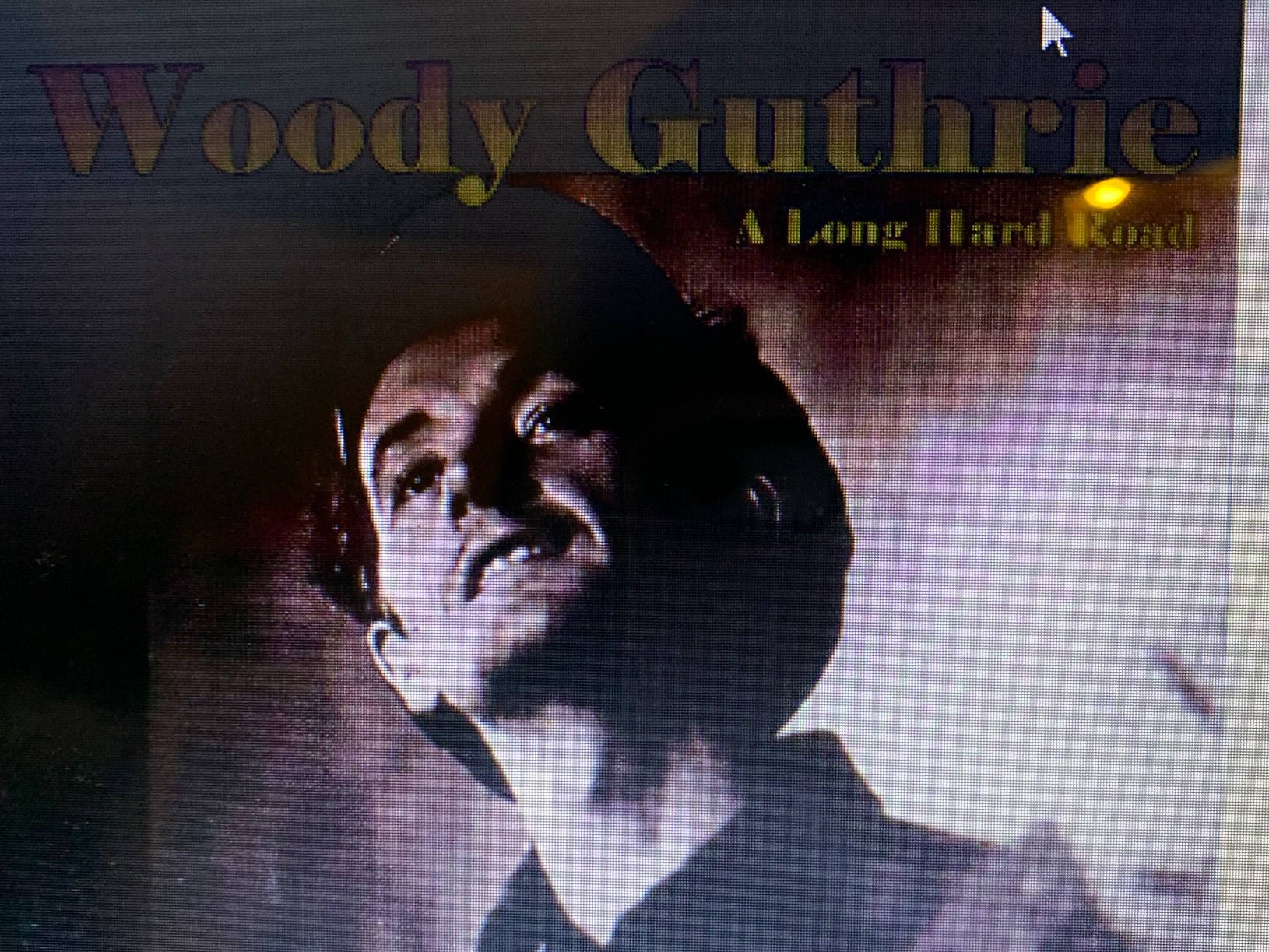 《漫長艱辛之路》伍迪·蓋瑟瑞 壁紙 — 伍迪·格思里（Woody Guthrie）的戲劇性肖像，在煙霧繚繞的背景中向上凝視，表情強烈。