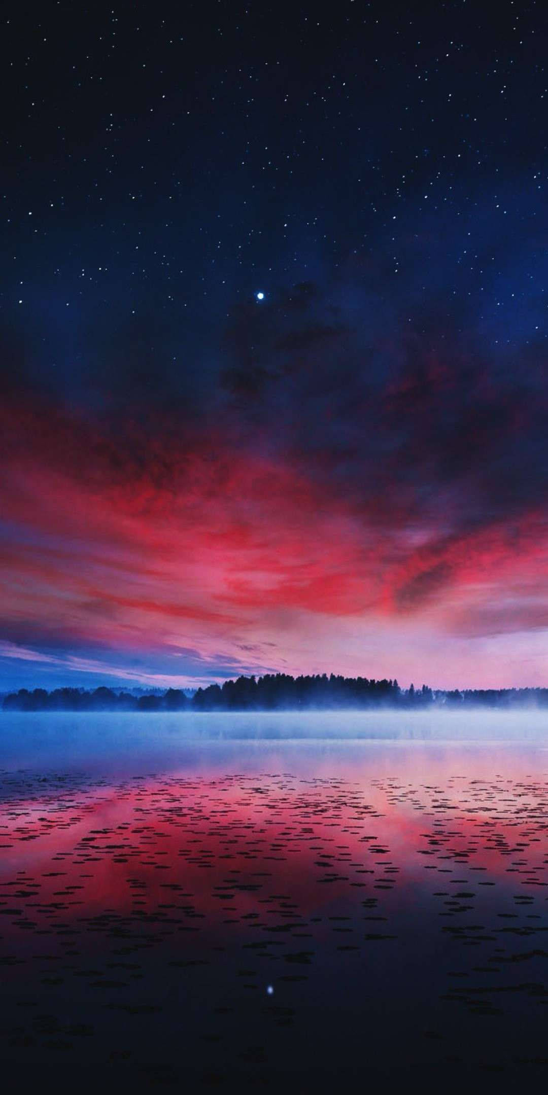 漸層多雲夜景 壁紙 — 寧靜的湖面映照著點綴著星星的鮮紅色和藍色暮色天空，遠處是森林的輪廓。