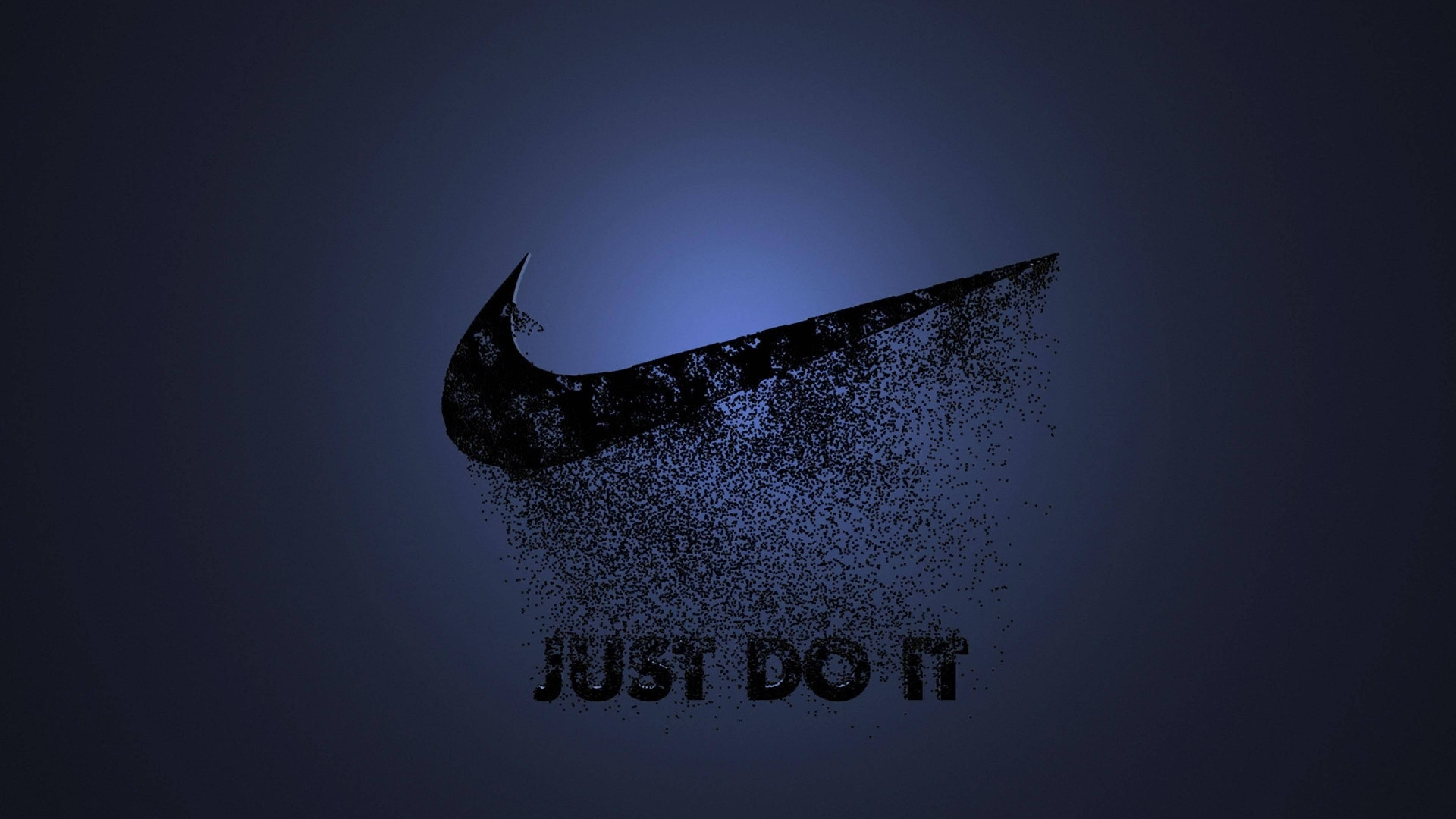 漸隱Swoosh標誌 壁紙 — 一個黑色Nike swoosh標誌在深藍色漸變背景上分解成粒子，下方有「JUST DO IT」文字。