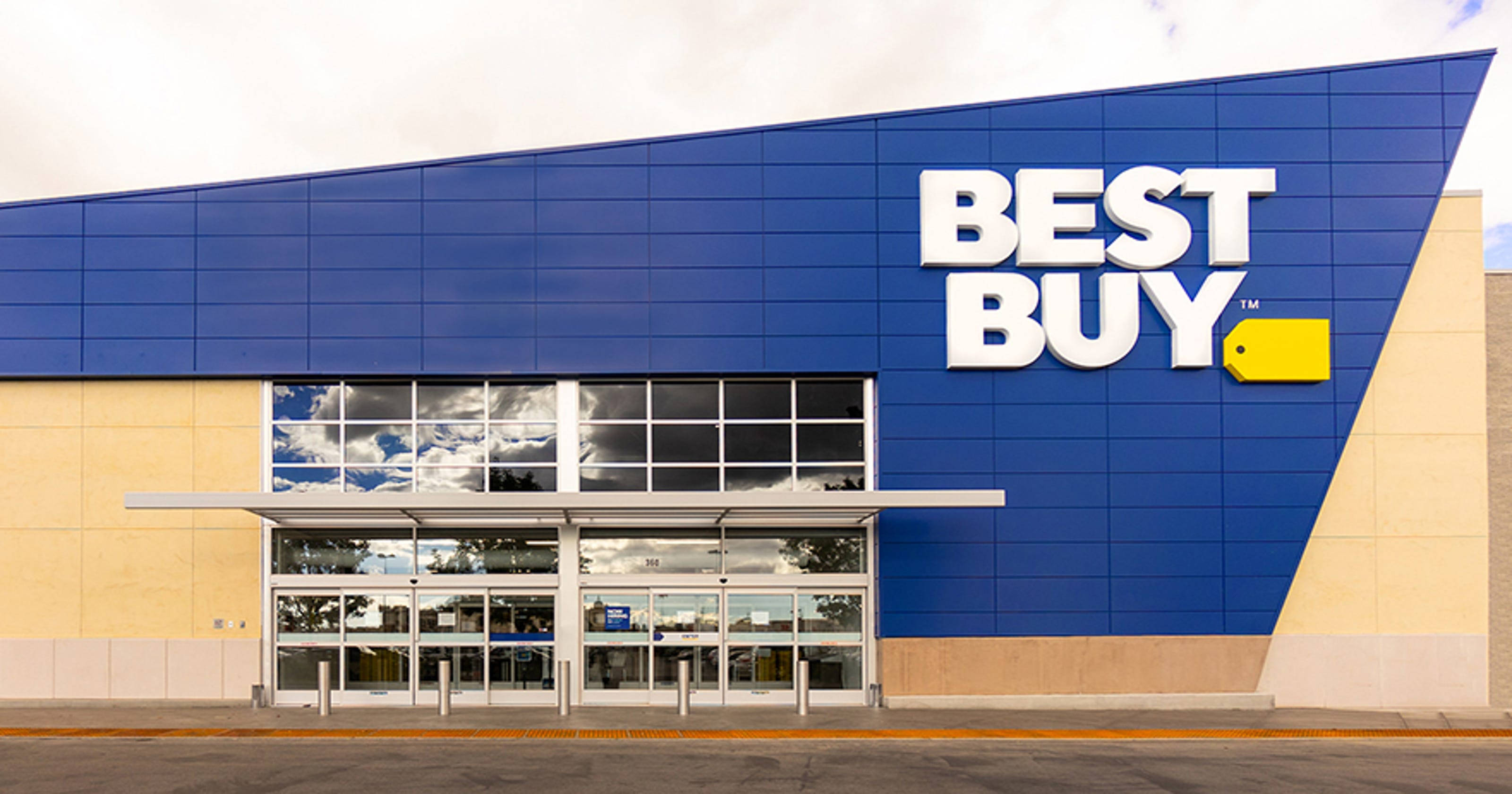 潔淨百思 buy 建築 壁紙 — 一間現代化的Best Buy商店，擁有醒目的藍色牆壁和大型玻璃門，天空多雲。