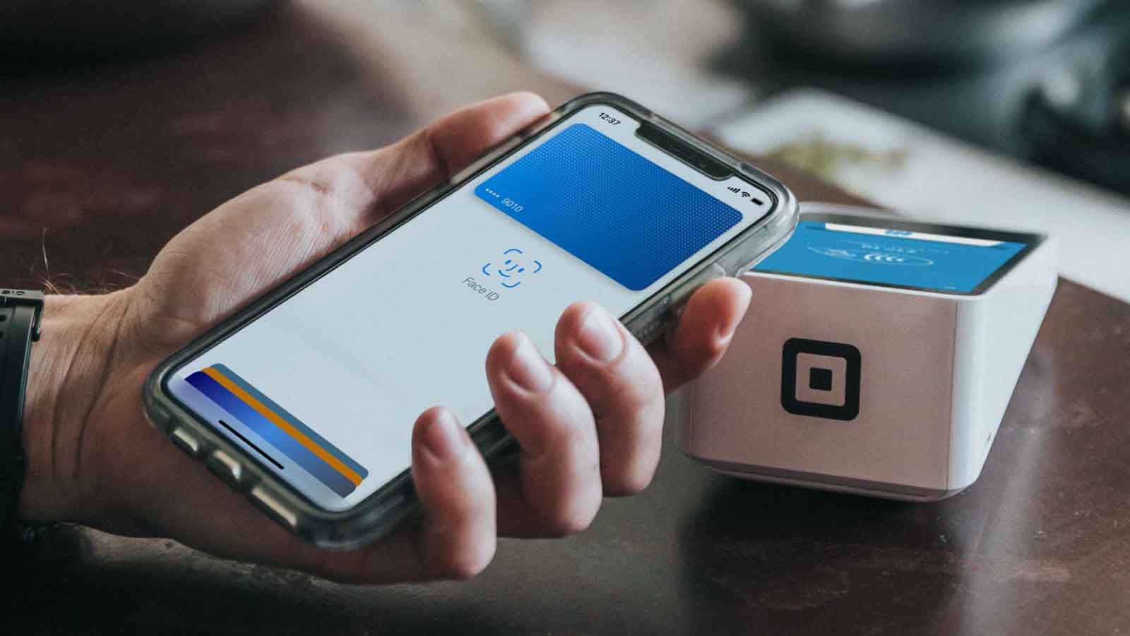 手在桌上用智能手機透過Square讀卡器進行非接觸式付款