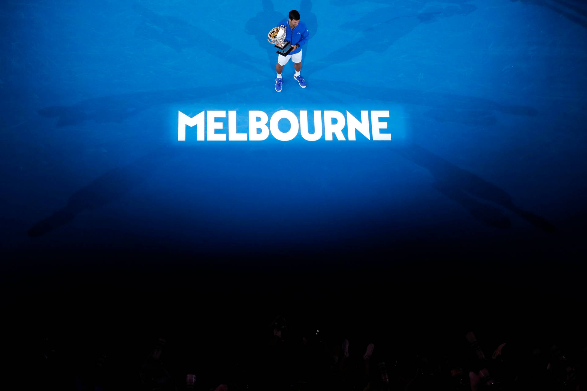 網球冠軍在「MELBOURNE」燈光下的藍色球場上高舉獎盃。