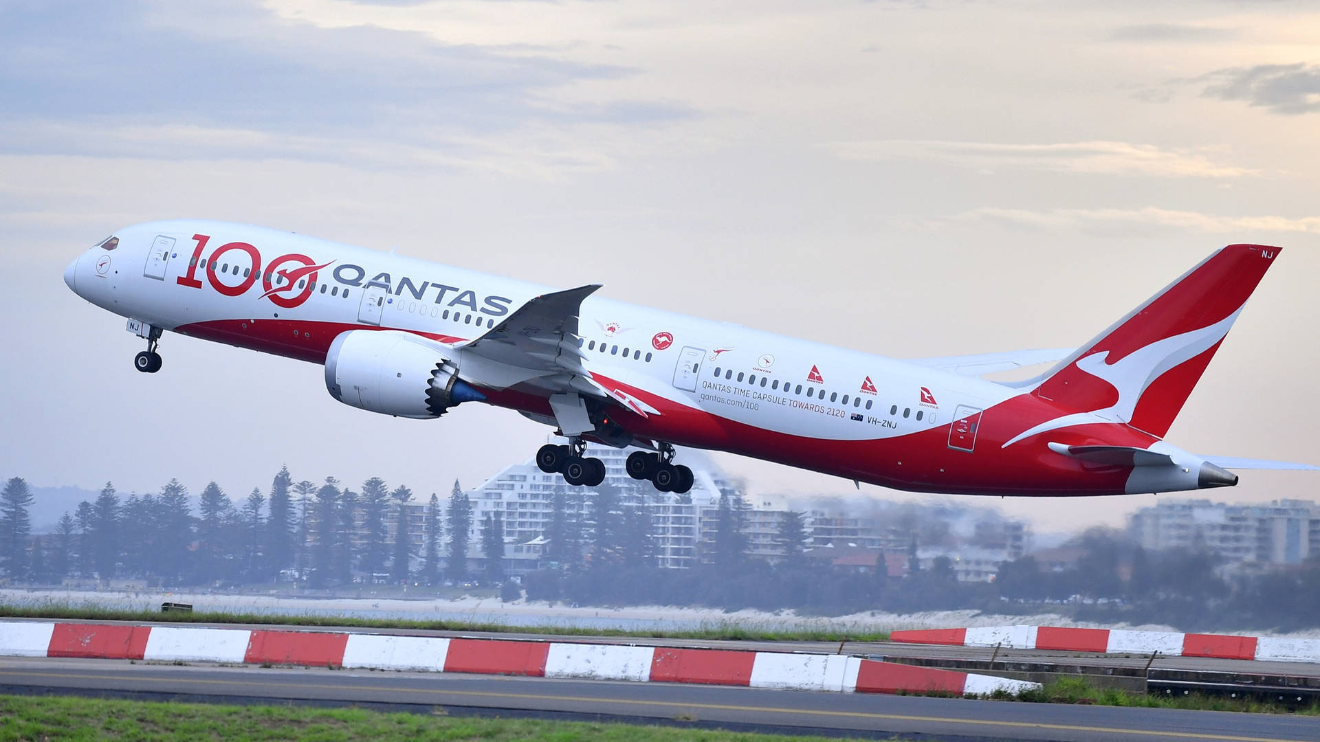 澳洲航空飛機在黃昏時分在城市建築附近起飛。
