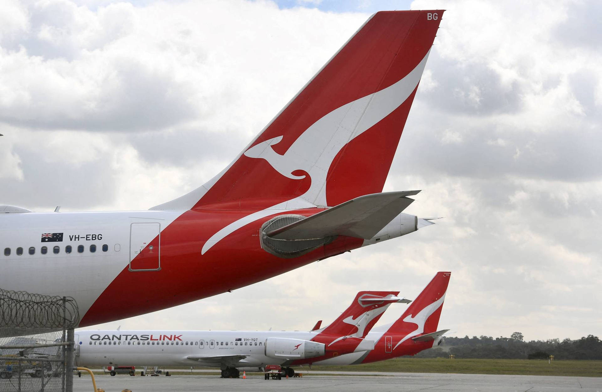 兩架QantasLink飛機停在多雲天空下的機場停機坪上。