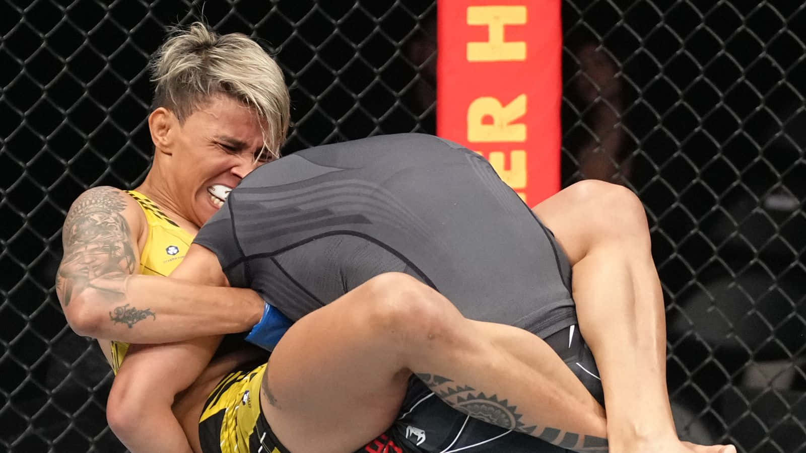 兩名女子MMA選手在八角籠內鎖定纏抱姿勢。