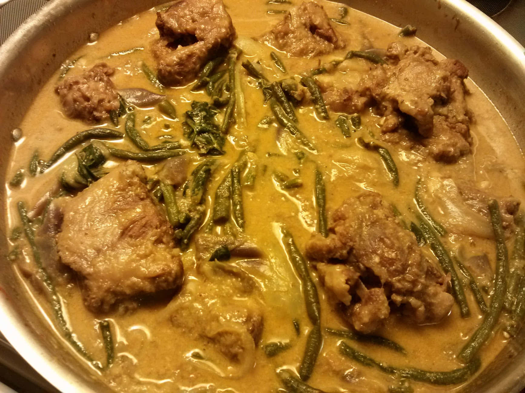 濃厚花生醬燉菜 Kare-Kare 壁紙 — 一鍋冒著蒸氣的濃郁黃咖喱，裡面有嫩肉塊和青豆在光澤的醬汁中燉煮。
