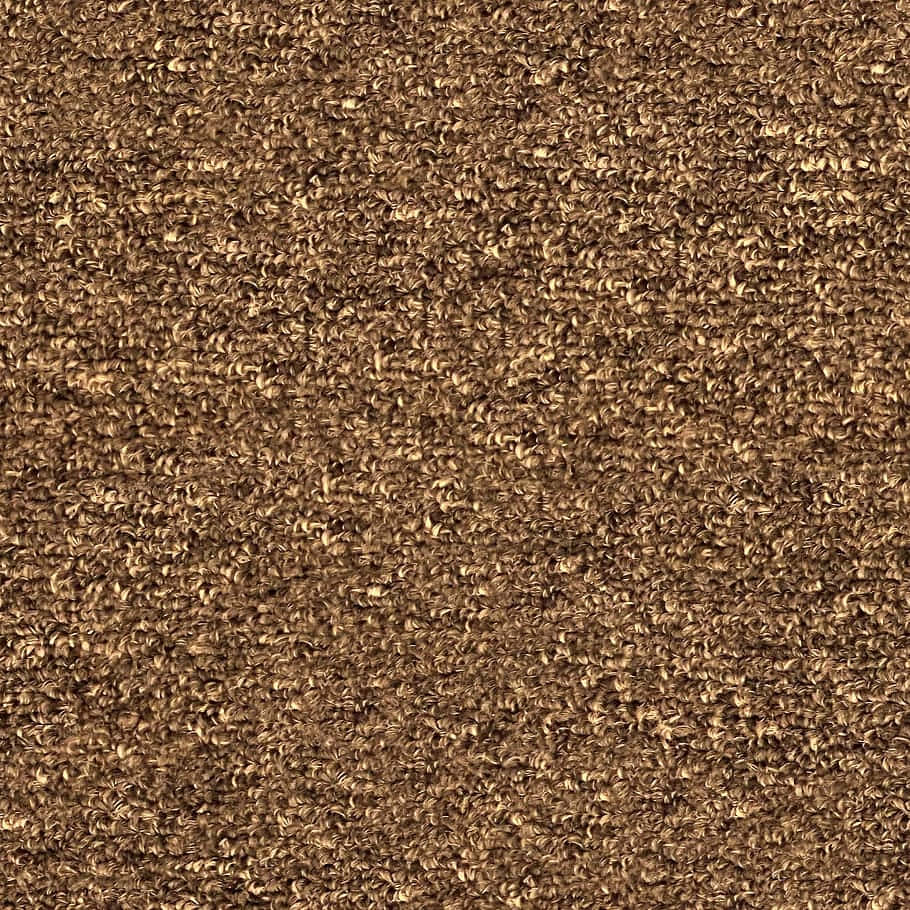 Carpet Texture 桌布 壁紙 — 濃密捲曲棕色地毯纖維的特寫，帶有溫暖的金色亮點和柔軟質感。