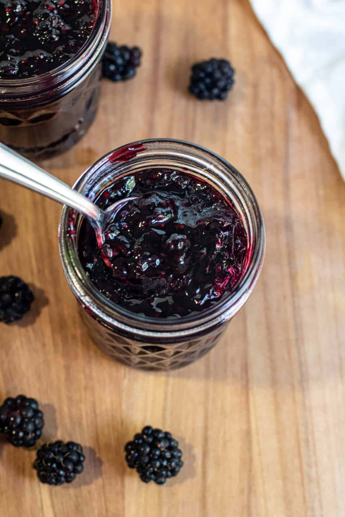 Blackberry Jam 桌布 壁紙 — 濃郁光澤的黑莓果醬玻璃瓶，新鮮莓果散落在溫暖的木板上。