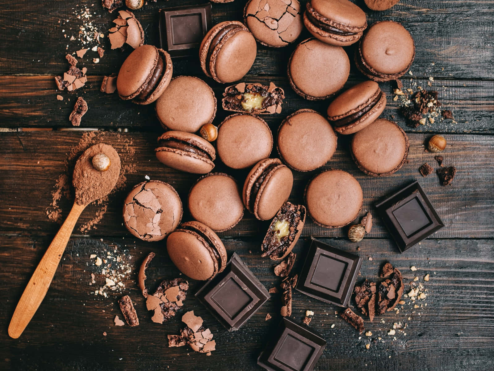 Brown Chocolate 桌布 壁紙 — 濃郁的朱古力馬卡龍和碎黑朱古力條散落在質樸的深色木質表面上，配以可可粉和榛子。