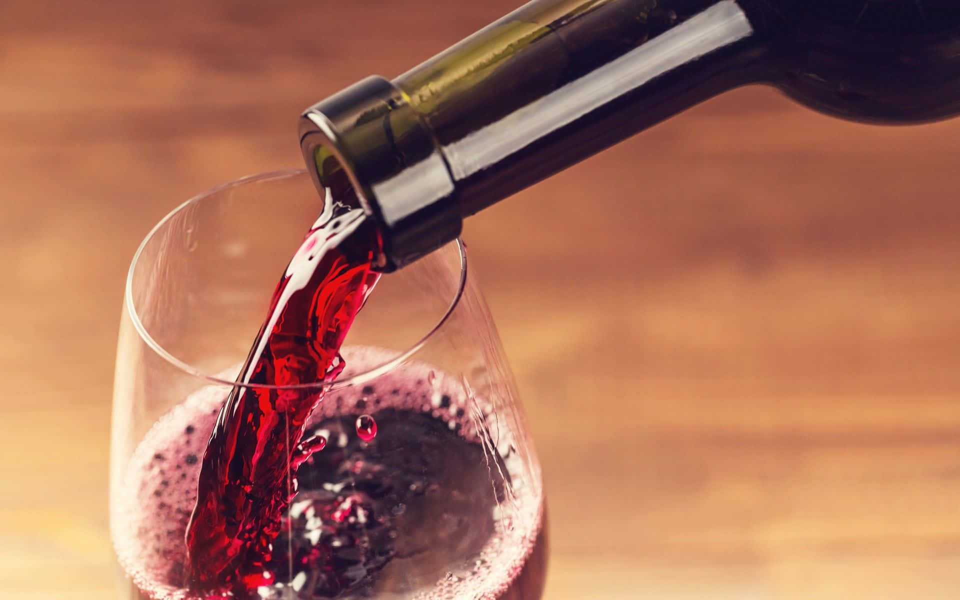 Red Wine Glass 桌布 壁紙 — 濃郁的紅酒從酒瓶動態地倒入玻璃杯中，置於溫暖的木質表面上。