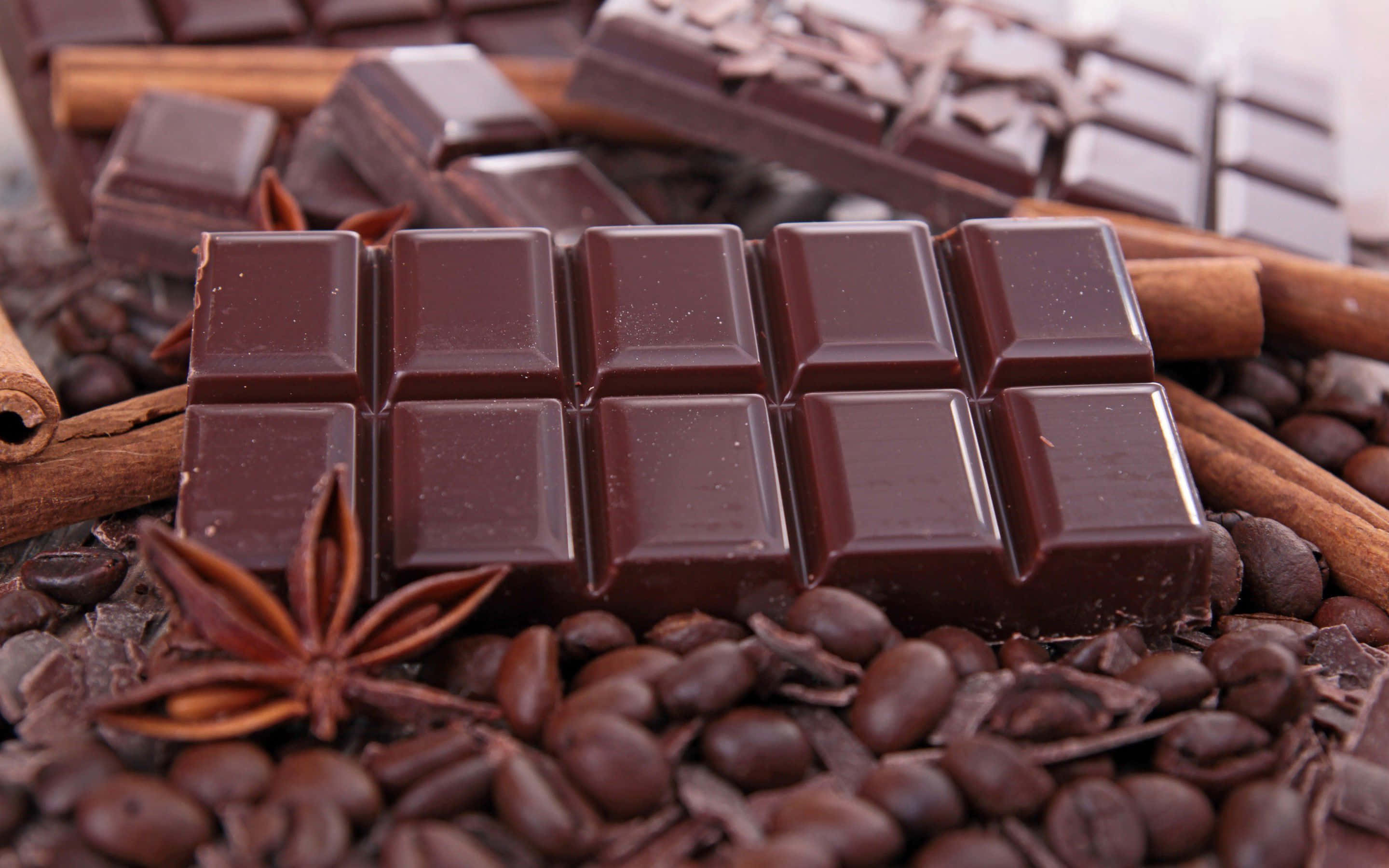 Brown Chocolate 桌布 壁紙 — 濃郁的黑朱古力條放在咖啡豆上，配以肉桂棒和八角，構成溫暖誘人的畫面。