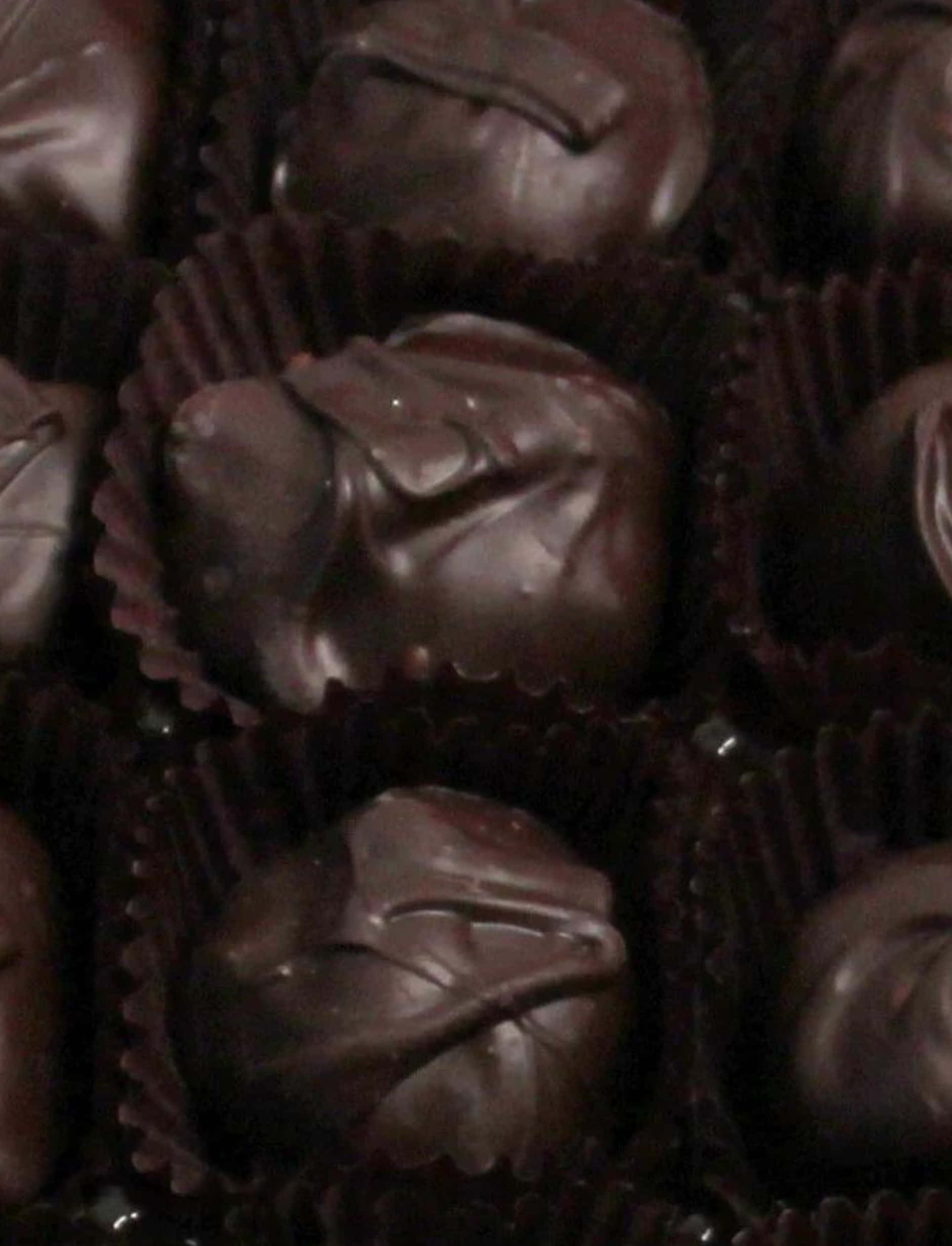Dark Chocolate 桌布 壁紙 — 濃郁的黑松露朱古力放在深棕色紙杯中，在溫暖昏暗的燈光下。