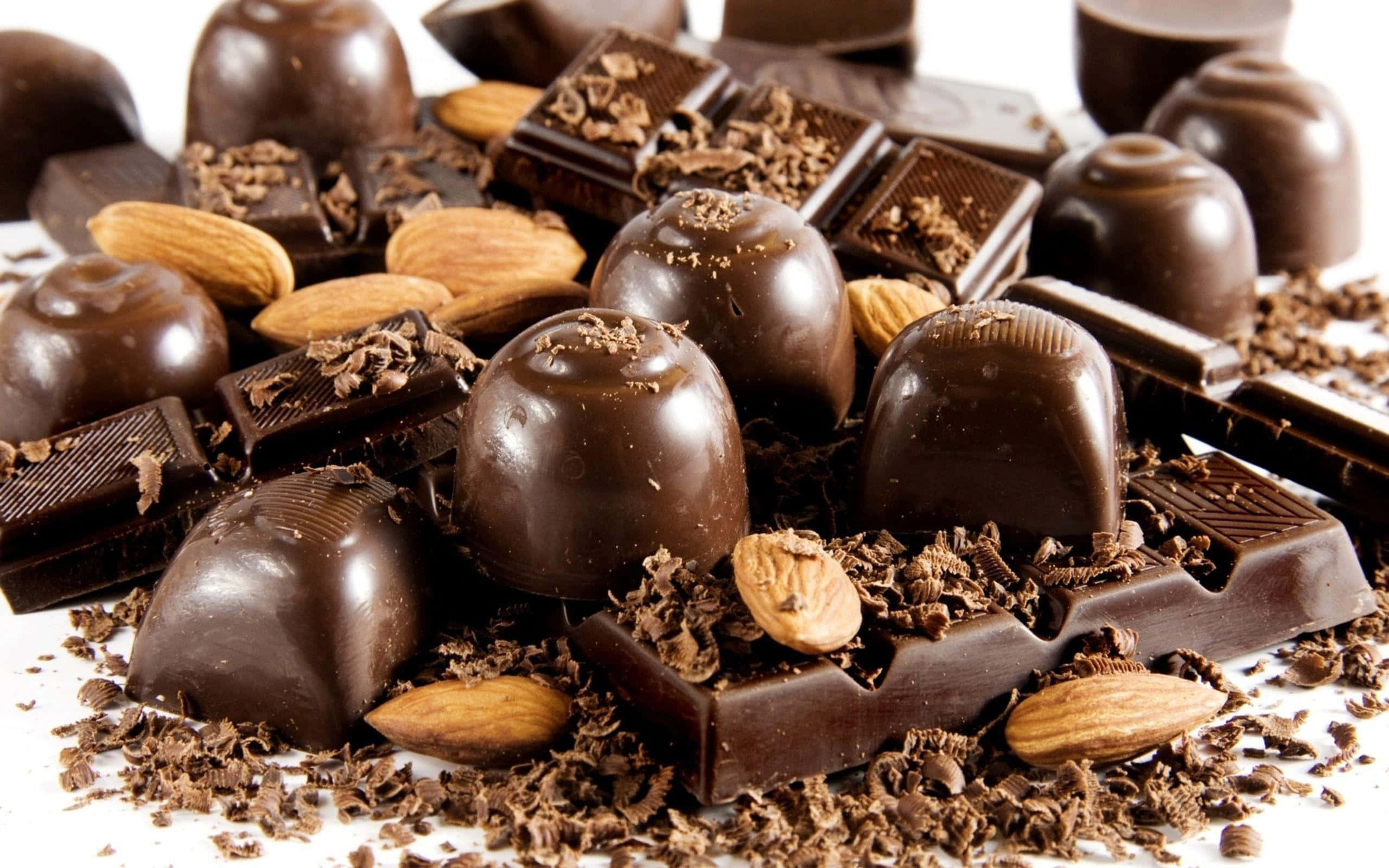 Brown Chocolate 桌布 壁紙 — 濃郁黑松露朱古力和朱古力條，配以整粒杏仁和可可碎屑，散落在白色表面上。