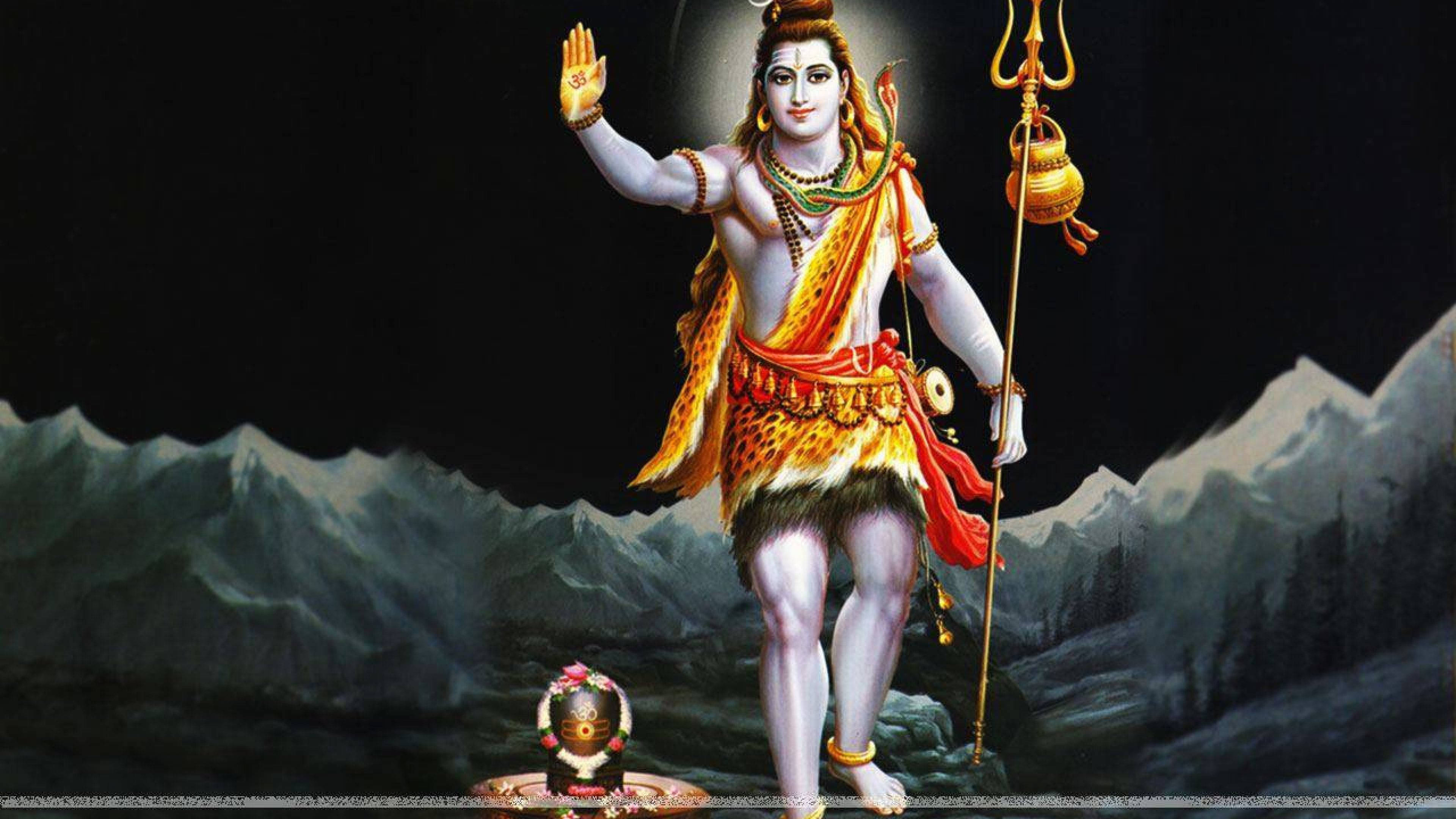 Lord Shiva 桌布 壁紙 — 濕婆神在雪山背景下威嚴站立，手持三叉戟和鼓，散發光芒並有蛇形裝飾。