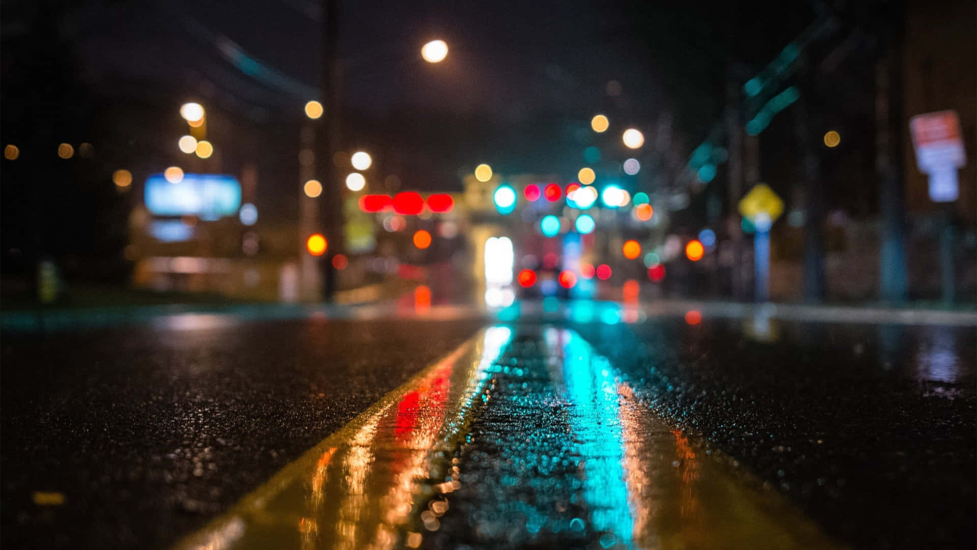雨夜街道，模糊的城市燈光反射在濕瀝青上。