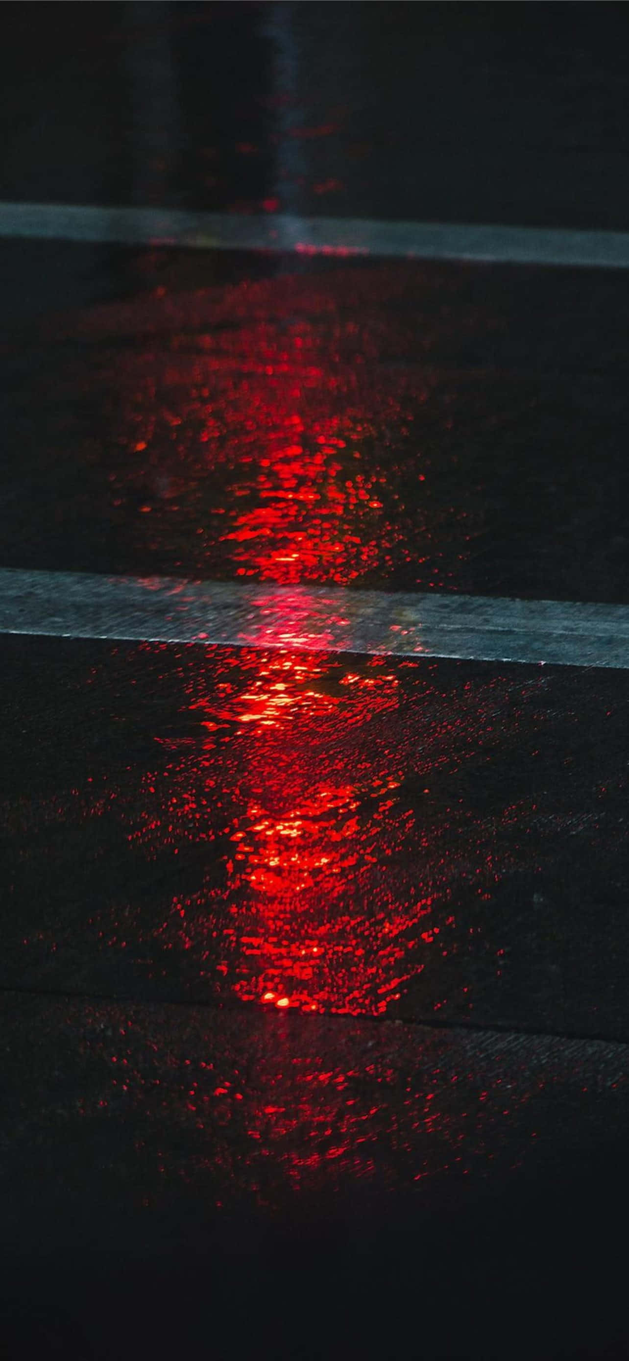 濕潤路面美學紅色背景 壁紙 — 在漆黑的夜空下，濕漉漉的瀝青條紋上反射出鮮豔的紅光。