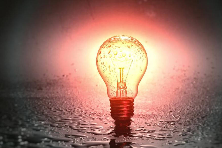 濕面燈泡簡約手機壁紙 壁紙 — 一個發光的燈泡帶有水珠，放在潮濕的表面上，在黑暗背景下投射出溫暖的紅色光芒。