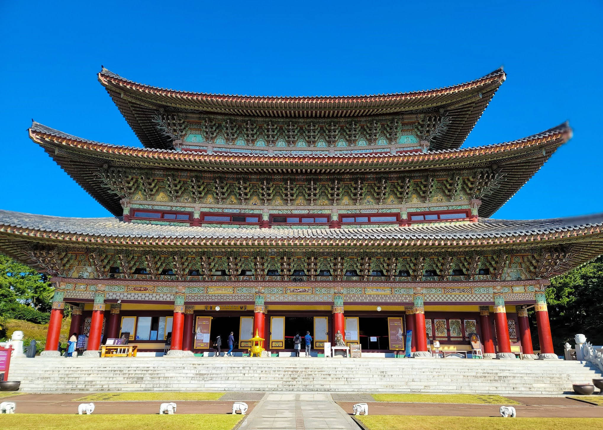 濟州島岩泉寺 壁紙 — 宏偉的傳統韓國寺廟，擁有分層屋頂和紅色柱子，在清澈的藍天下。