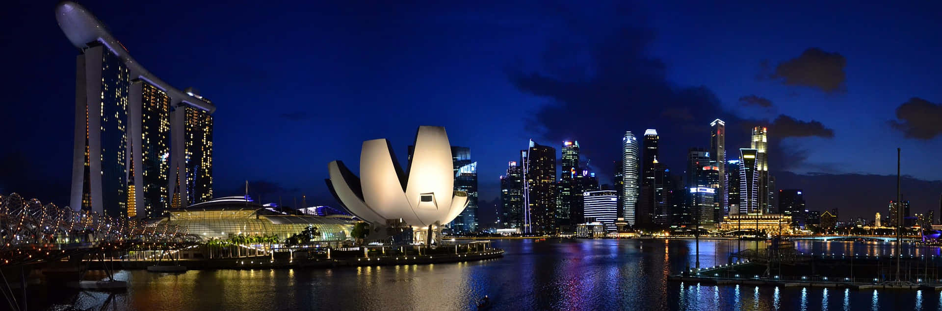 夜晚的新加坡天際線，燈火通明的建築物和海濱倒影。