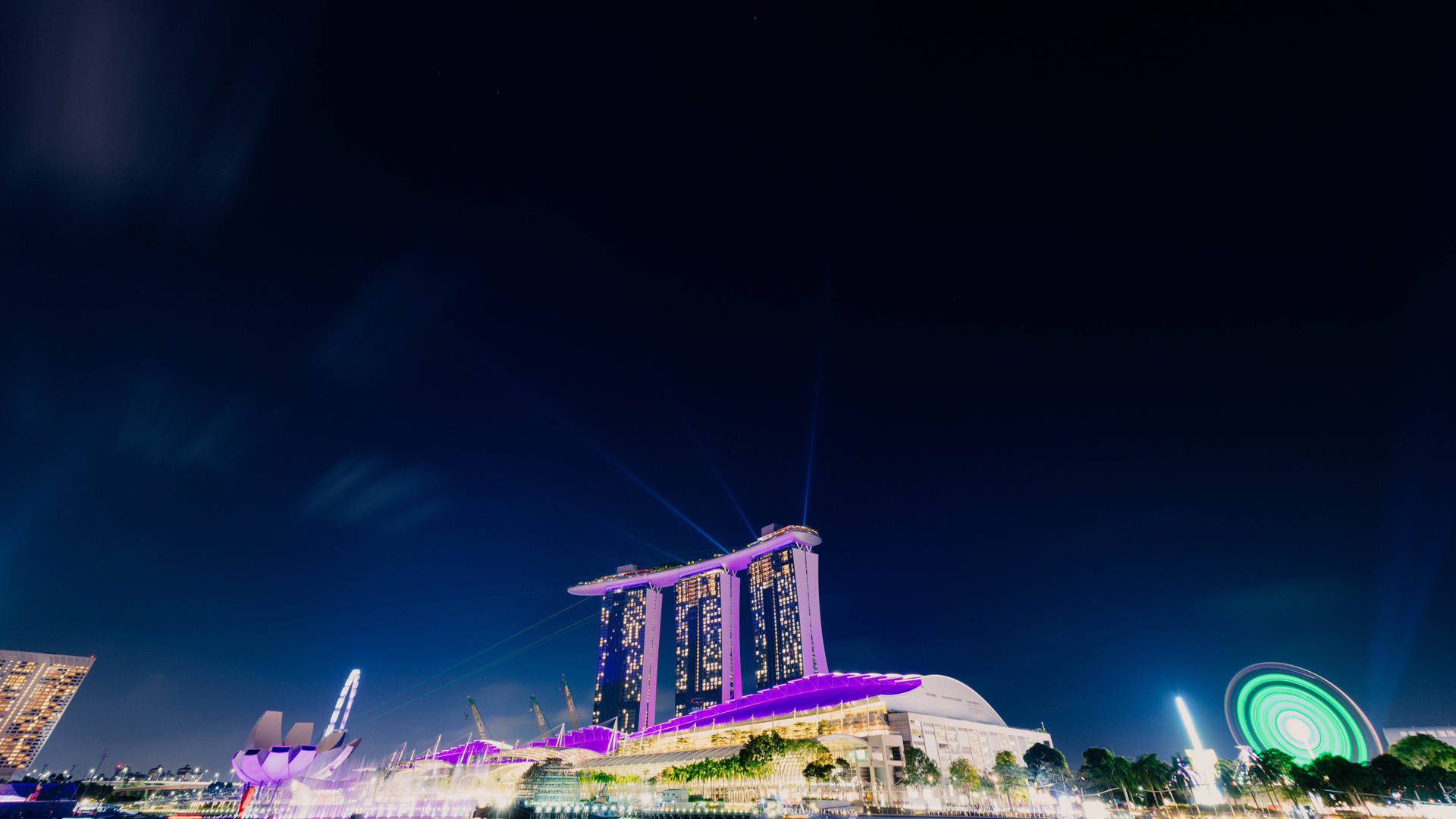 濱海灣金沙酒店在夜晚以紫色燈光和激光束照亮。