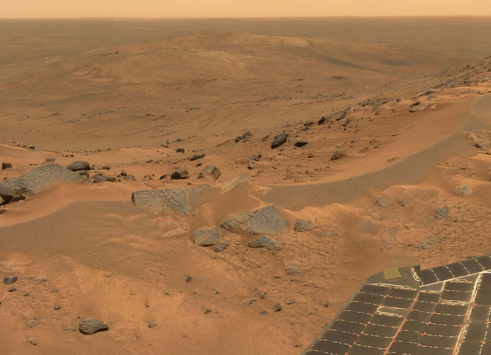 Mars Landscape 桌布 壁紙 — 火星表面嘅航拍圖，前景係岩石地形同太陽能板，天空係朦朧嘅橙色。