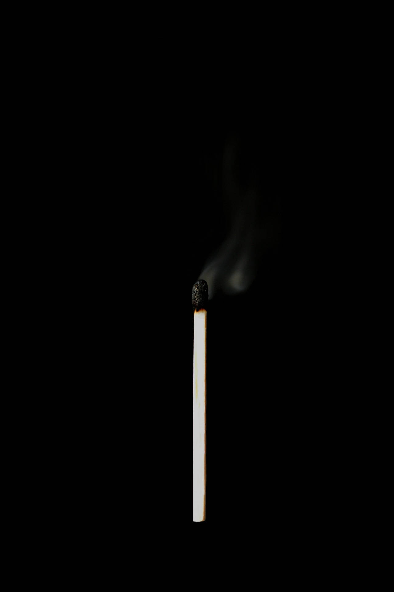 一根點燃的火柴在黑色背景上冒煙