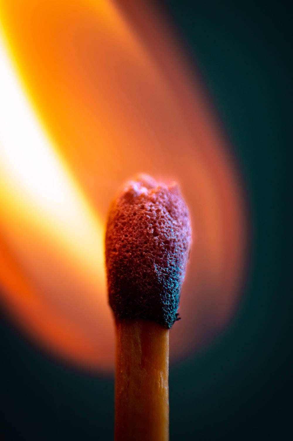 一根點燃的火柴，在黑暗背景上閃耀著明亮的火焰。