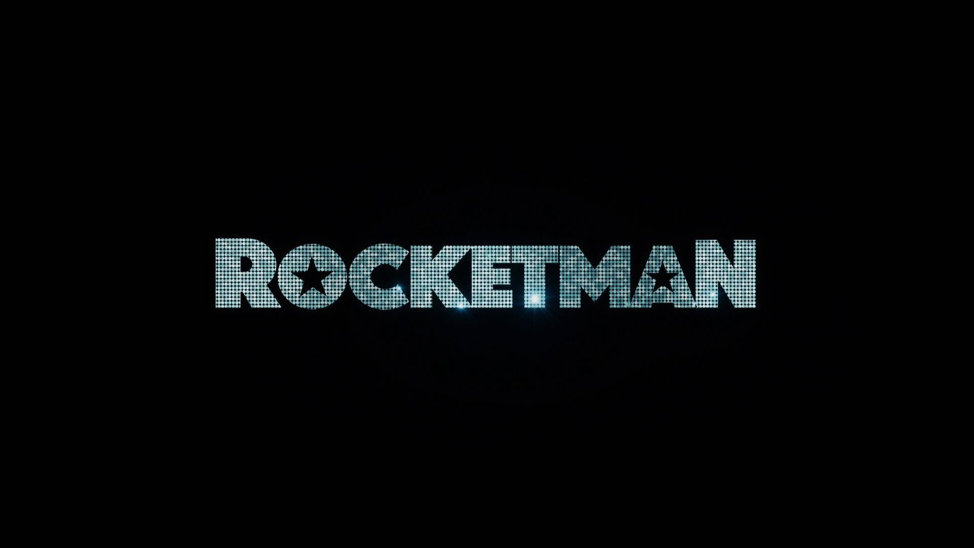 火箭人藍色文字 壁紙 — 「ROCKETMAN」一詞在帶有星星點綴的黑色背景上以閃爍的藍色像素發光。