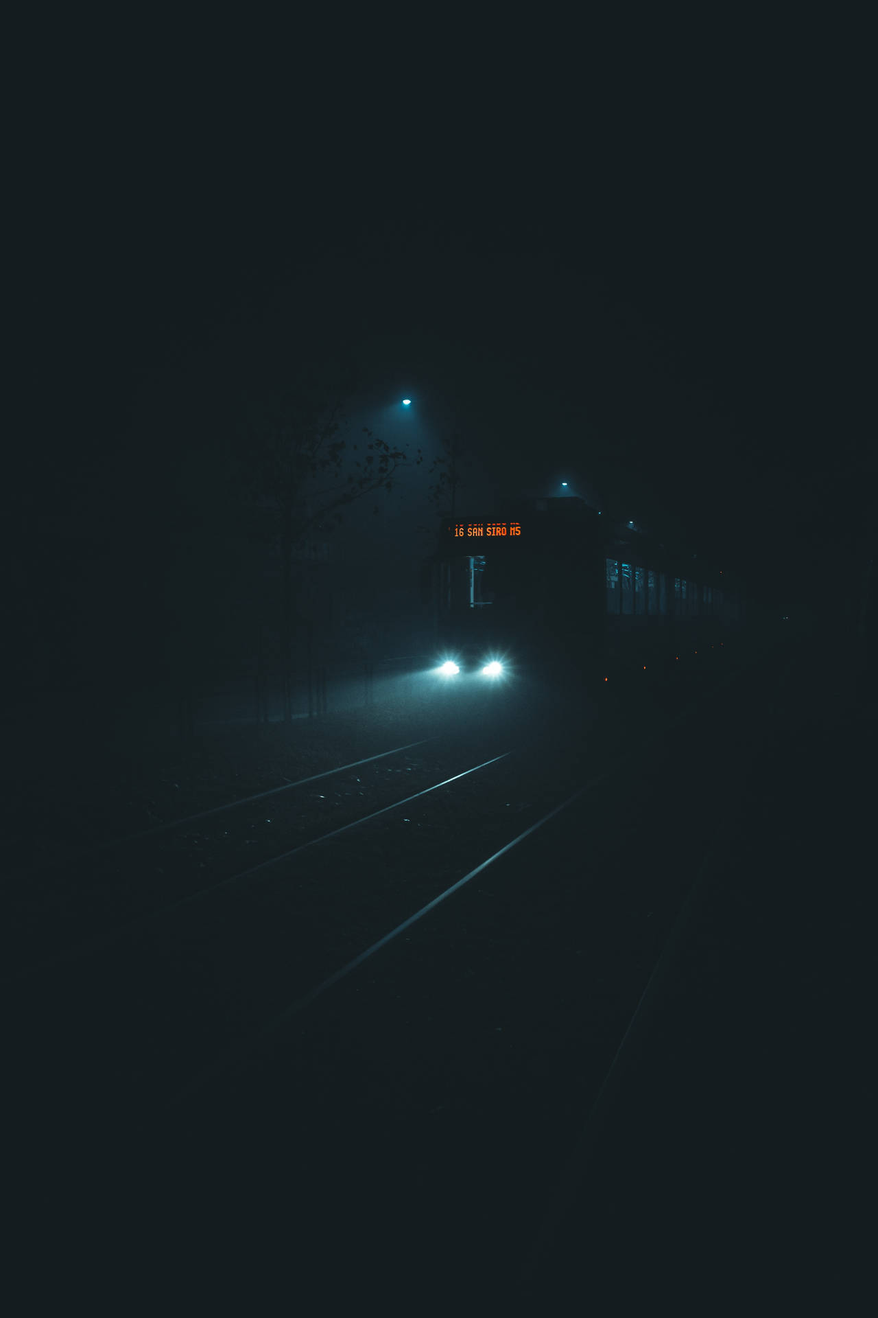 火車頭燈在夜間穿透黑暗軌道上的霧氣。