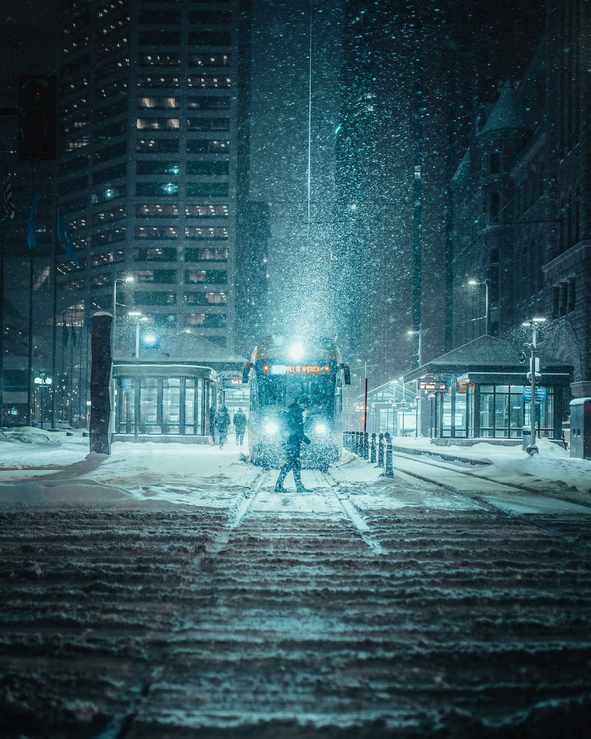 在雪夜城市中，一個人走向電車，燈光明亮。