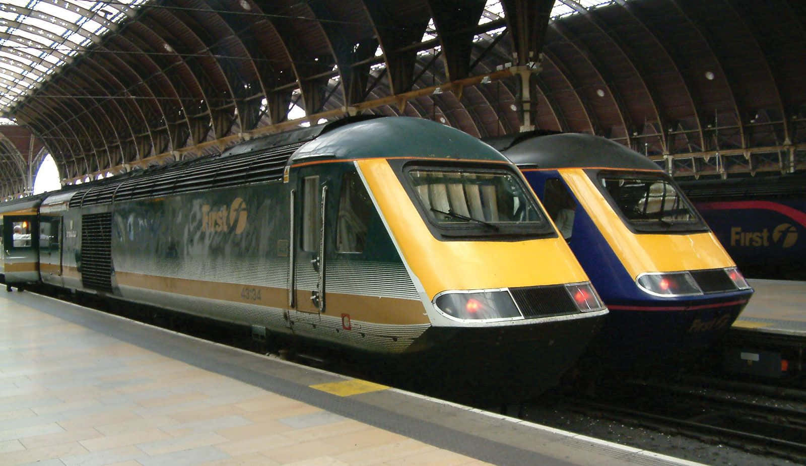 兩輛現代列車在大型拱形屋頂下的車站月台上。