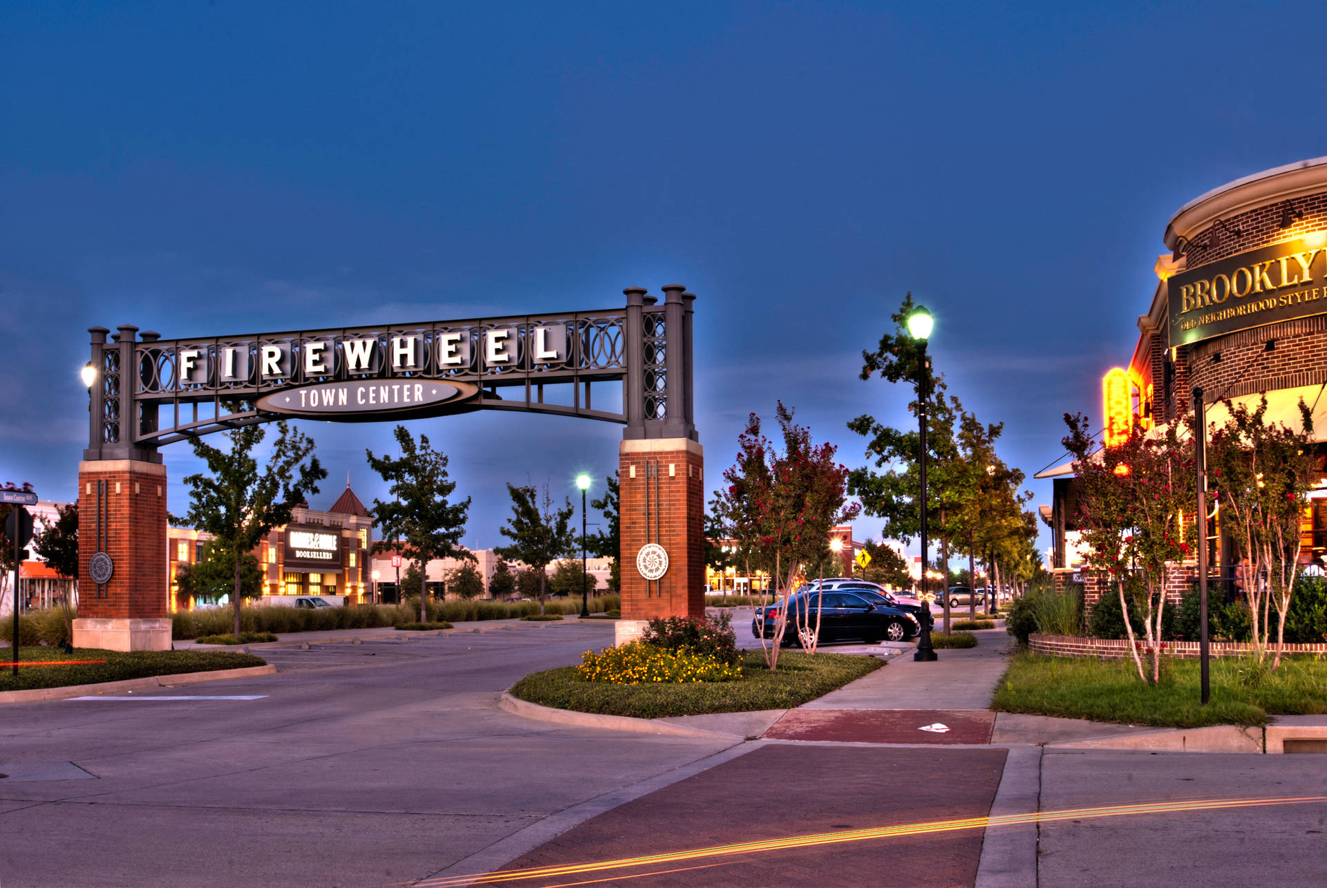 黃昏時 Firewheel Town Center 入口拱門，帶有發光標誌和街燈。