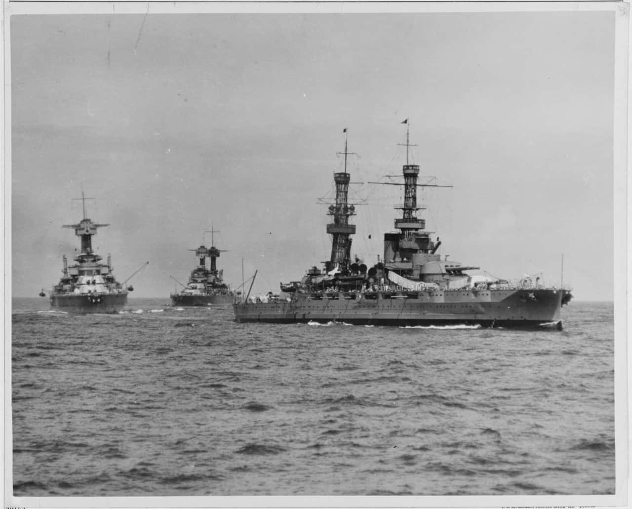 灰艦隊展開戰鬥 壁紙 — 三艘威嚴的戰艦在陰天之下，於波濤洶湧的海面上編隊航行，這是一張歷史性的黑白照片。