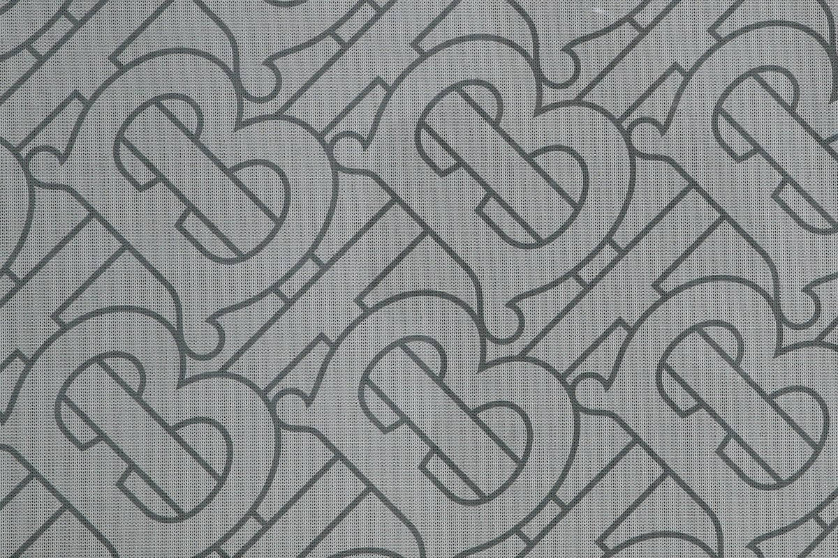 帶有重複風格化B字母字母組合圖案的灰色布料。