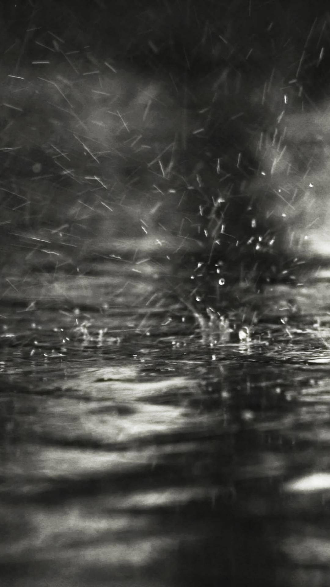 雨滴在黑暗的水面上飛濺散開的單色畫面。