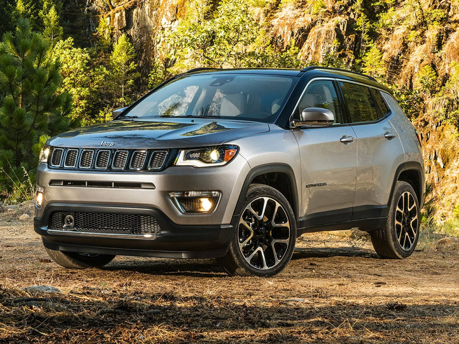 銀色Jeep Compass停泊在樹林岩石區的泥濘小徑上。