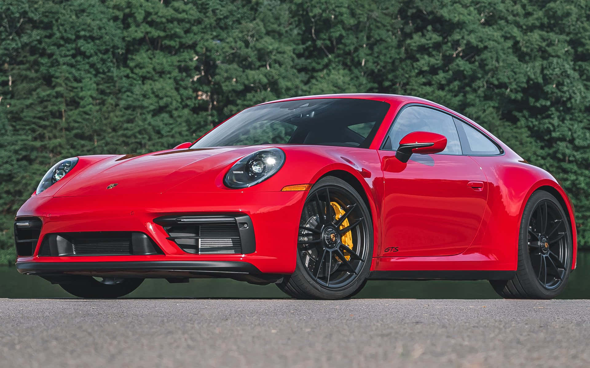 紅色保時捷 911 GTS 停在路上，後面有綠樹