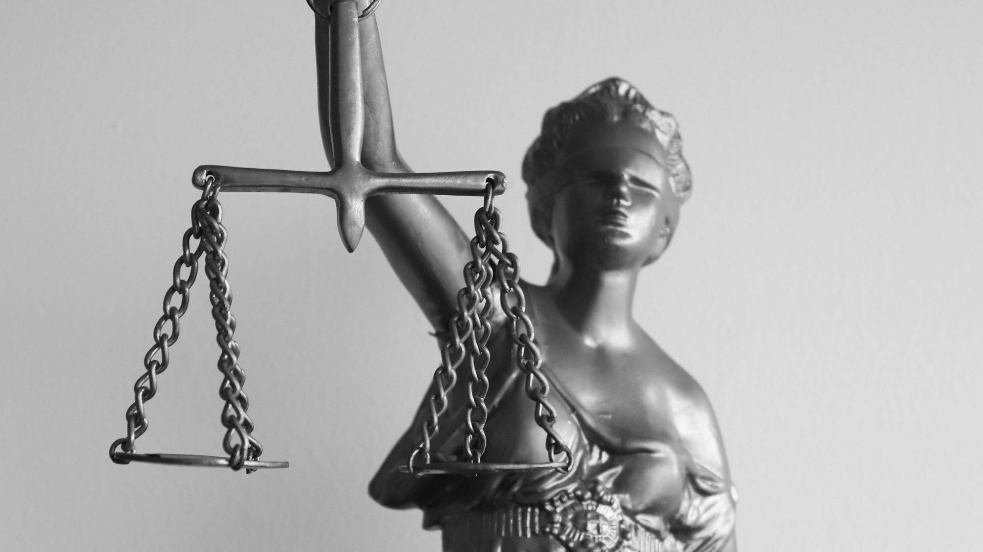 灰色正義女神 壁紙 — 單色正義女神雕像，手持天秤與劍，背景簡潔。