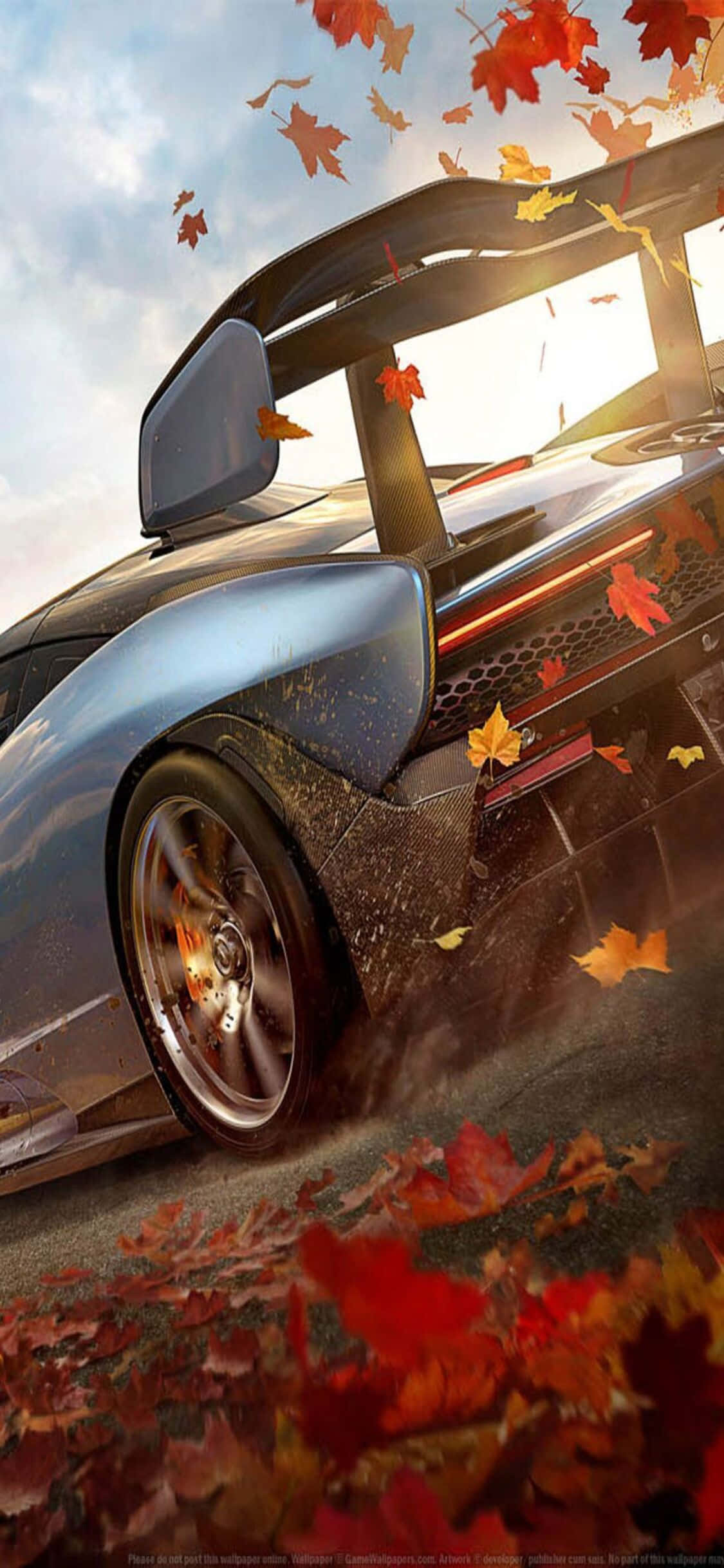 灰色法拉利 iPhone X《Forza Motorsport 7》背景 壁紙 — 一輛時尚的藍色跑車在森林中疾馳，秋葉在車輪周圍旋轉。