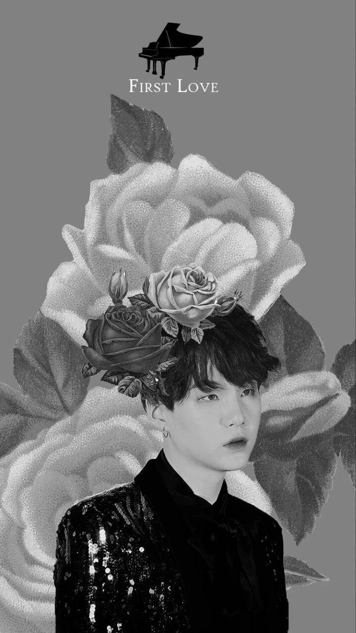 BTS Suga First Love 壁紙 — 灰色背景上，一位年輕男子頭頂有玫瑰和三角鋼琴圖示的黑白肖像。