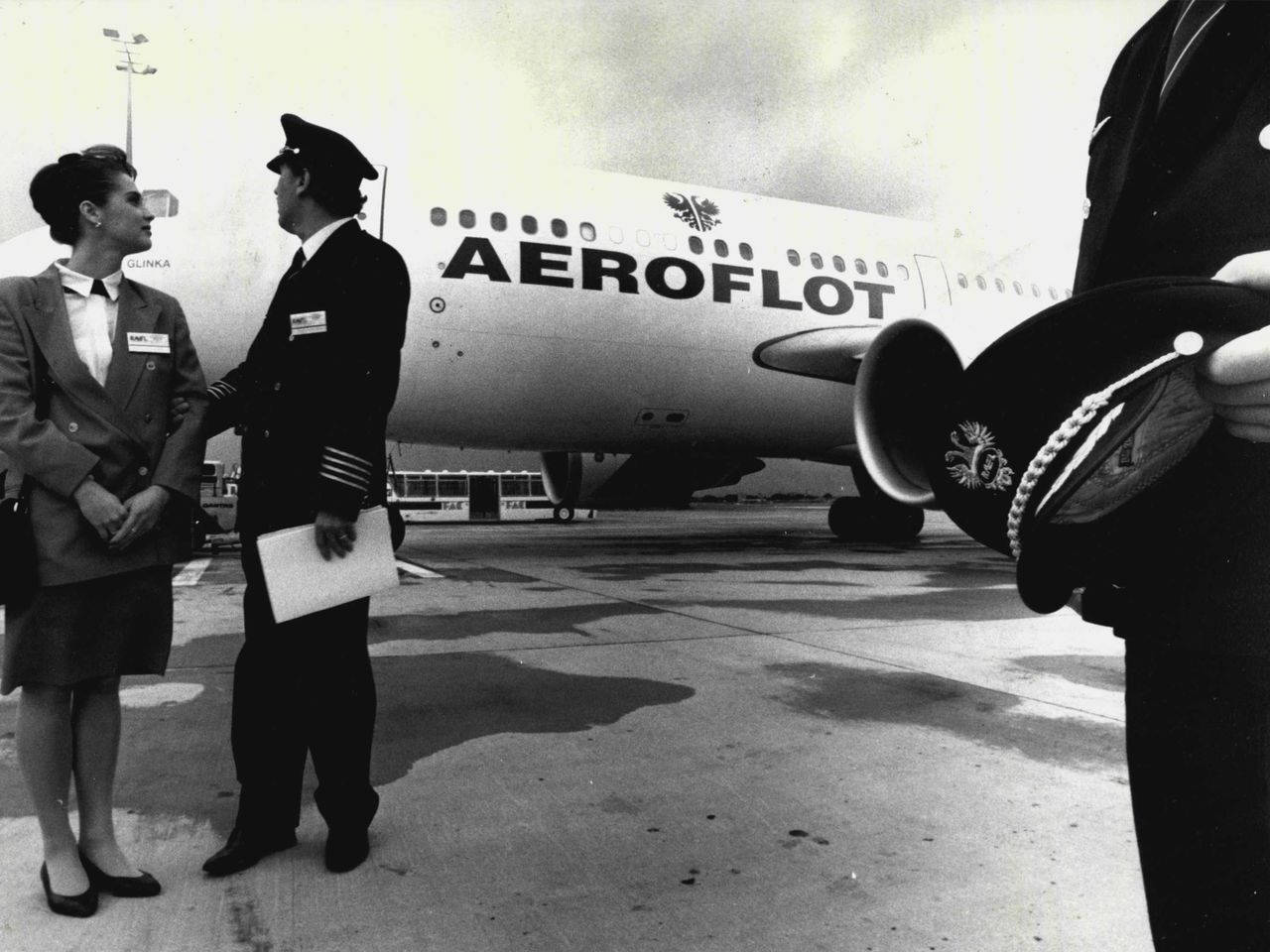 身穿制服的航空公司機組人員在停機坪上Aeroflot飛機旁迎接乘客。