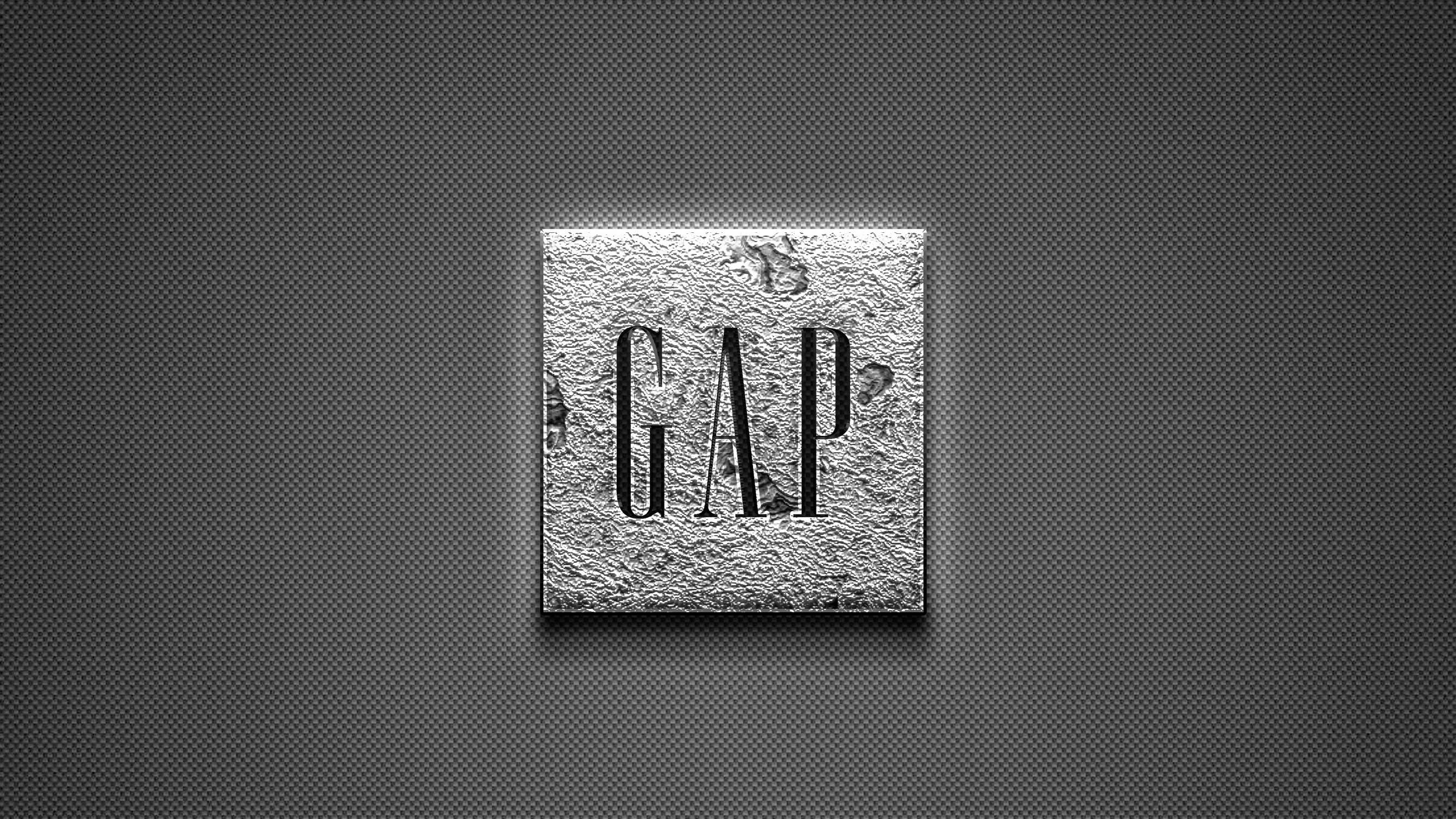 灰階紋理 Gap 標誌壁紙 壁紙 — 一個帶紋理的金屬正方形，在深灰色穿孔背景上以粗體字壓印了GAP這個詞。